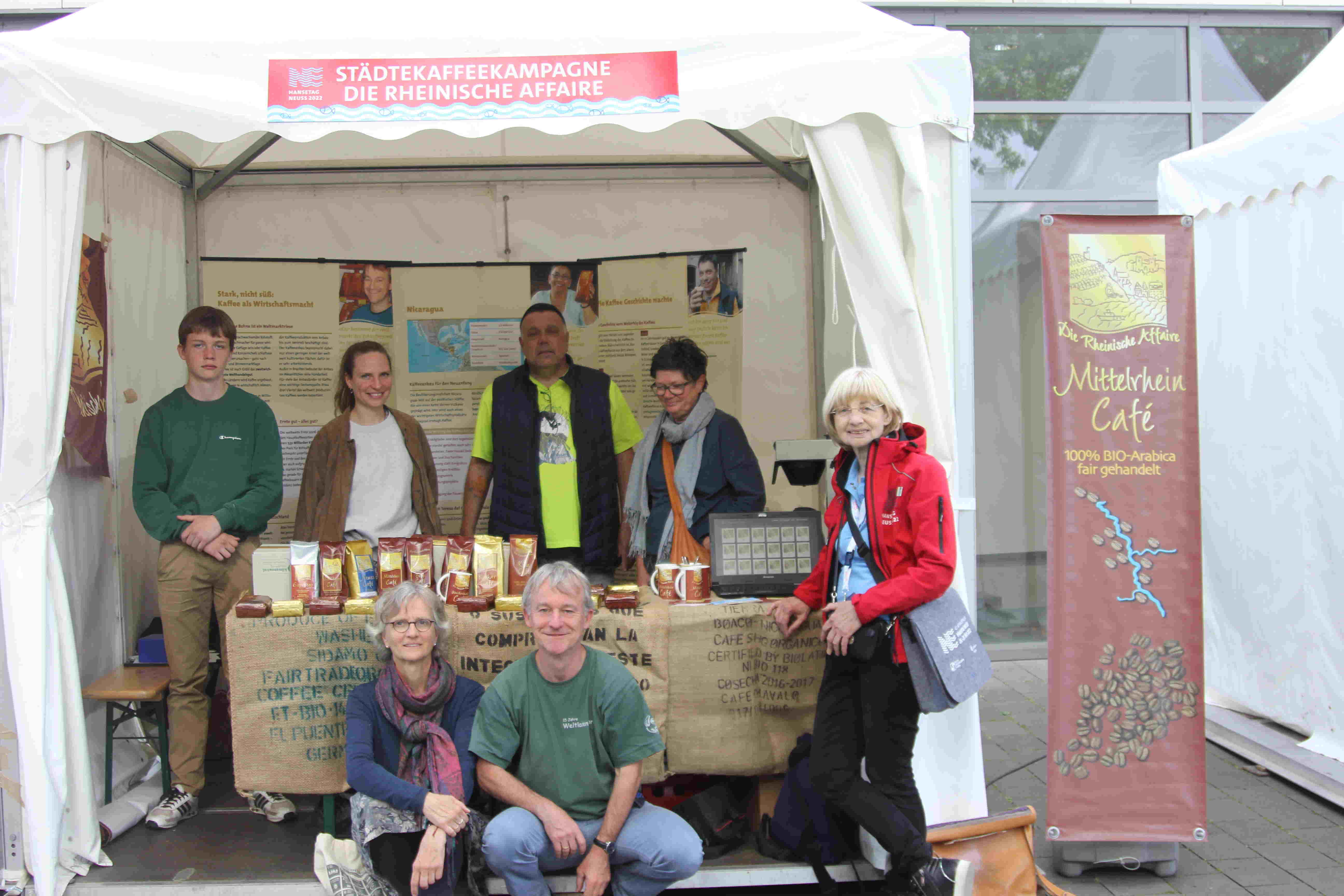 Ein Gruppenbild von Vertreterinnen und Vertretern der Rheinischen Affaire, umrahmt von Ausstellung und Kaffees, am Romaneum in Neuss